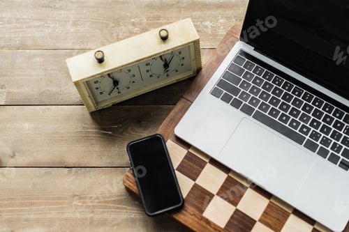 Preview: Chess clock, smartphone, laptop and chess board on wooden surface