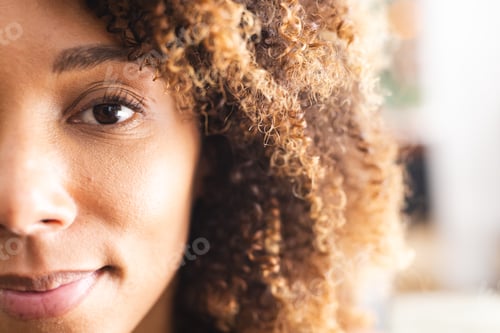 Preview: Close-up of a biracial woman with curly hair and warm brown eyes