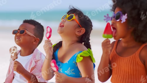 Preview: Group of children eating ice cream while having a picnic on the beach during summer vacation.