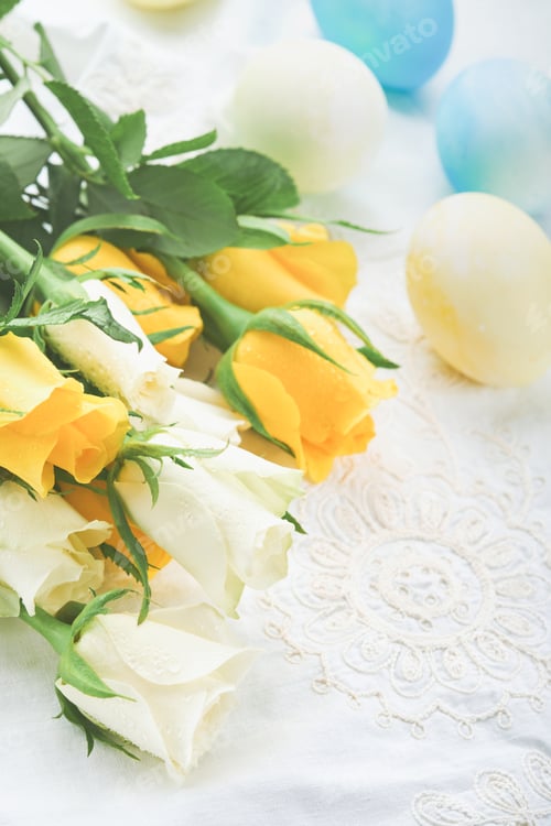 Preview: Happy Easter. Easter eggs on rustic table with white and yellow roses. Natural dyed colorful eggs in