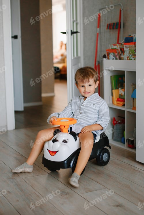 Preview: Little Boy On Toy Car Smiling In Cozy Kids Room