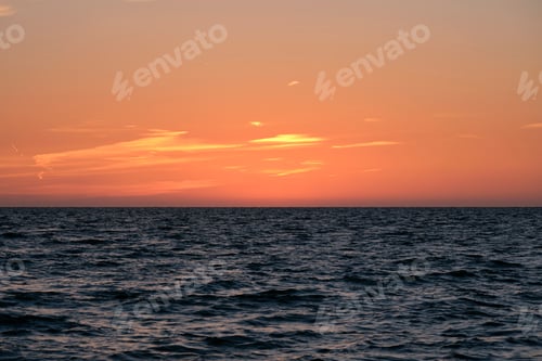 Preview: Dramatic bright red sky at ocean sunset, soft evening clouds over sea