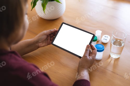 Preview: Senior woman with medicines on table using laptop during online doctor consultation, copy space
