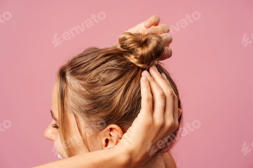 Preview: Woman Styling Her Hair Into a Messy Bun