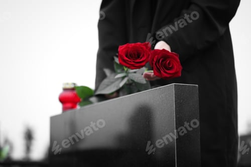 Preview: Woman with red roses near black granite tombstone outdoors, closeup. Funeral ceremony