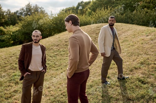 Preview: Stylish men showcase autumn fashion in a natural field during a sunny afternoon