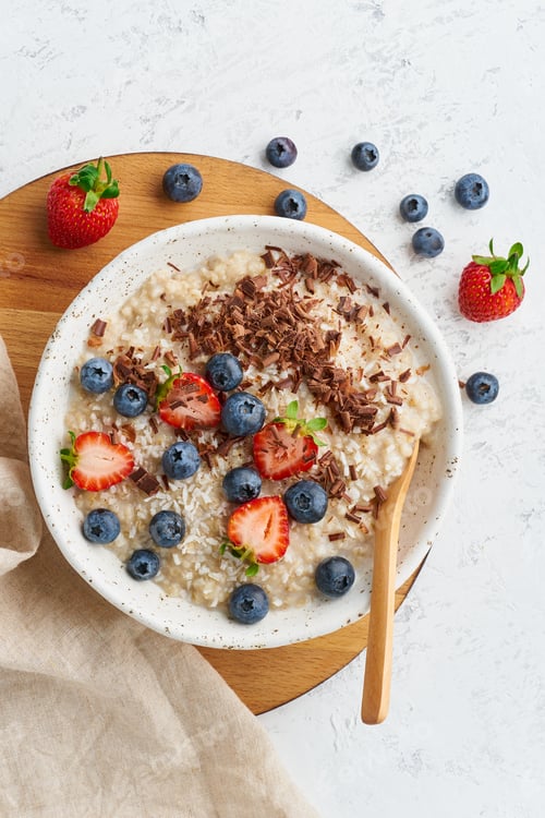 Preview: Oatmeal porridge rustic with berries and chocolate, dash diet, on white wooden background top view