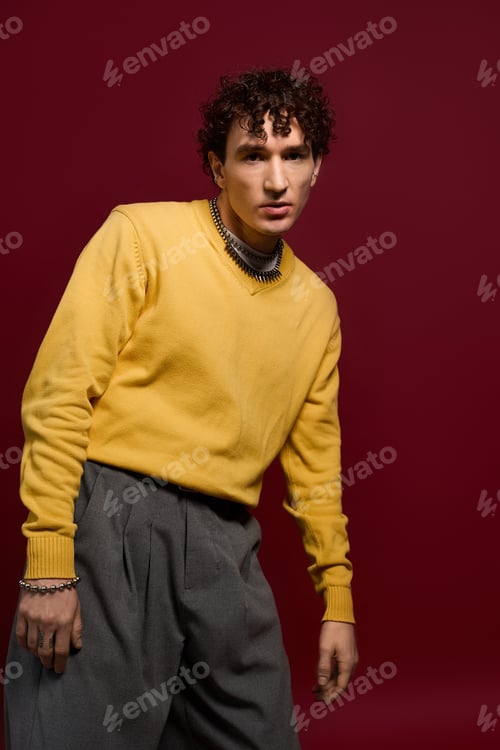 Preview: Handsome man showcases modern fashion with a striking yellow sweater and tailored trousers