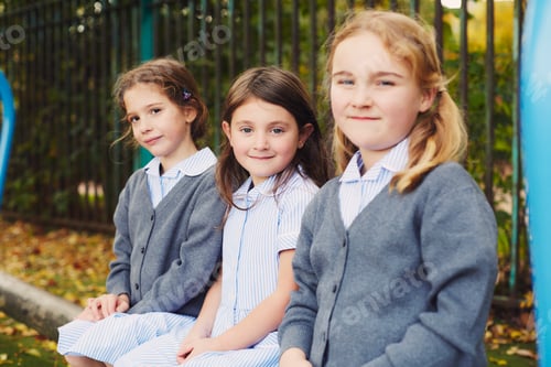Preview: Three young girls smiling on a park bench in school uniforms