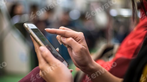 Preview: Asian woman sit down in metro and holds smartphone. Passenger using phone