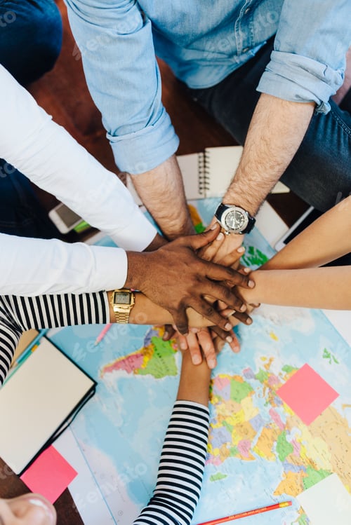 Preview: Group of friends stacking hands above world map