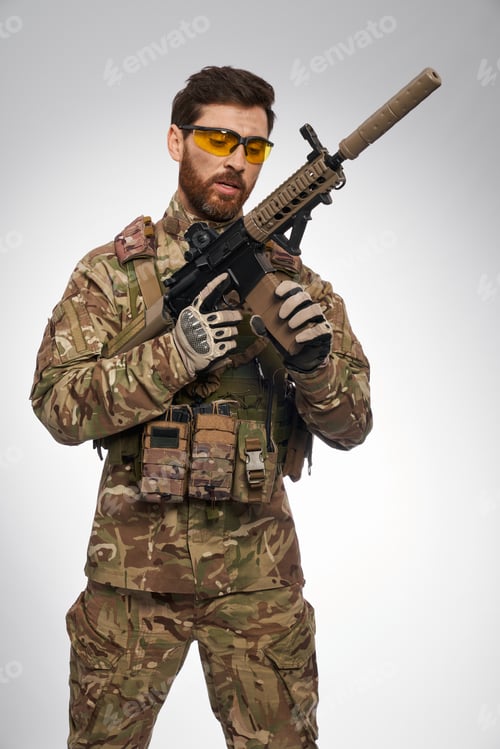 Preview: Focused soldier in camouflage outfit recharging sniper rifle.