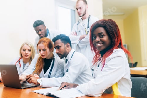 Preview: Multiracial team of young doctors working on laptop computer in medical office
