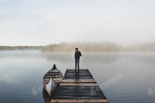 Preview: Man standing on pier, looking at view, rear view