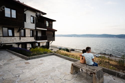 Preview: Brother with sister sitting on a bench and looking at the sea in Nessebar, Bulgaria.