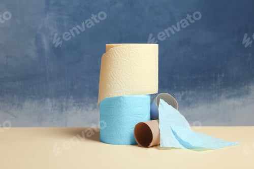 Preview: Full and empty toilet paper rolls on table against color background