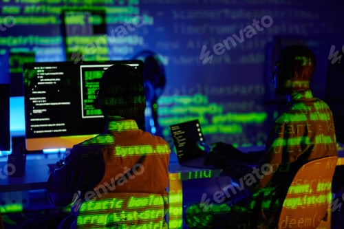 Vista previa: Rear view of two young programmers sitting in front of computers by desks
