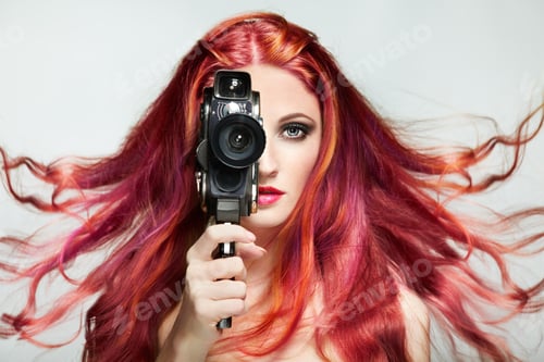 Preview: Beautiful young woman using a retro video camera