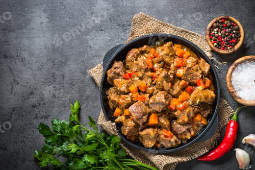 Preview: Beef stew with vegetables in iron pan on black.