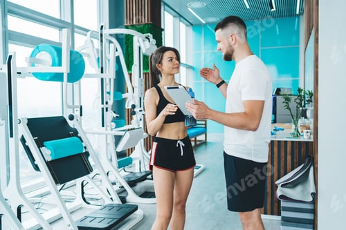 Preview: Trainer with sportswoman in gym