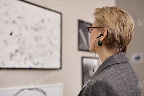 Preview: Middle Aged Caucasian Woman Observing Artwork While Listening to Audio Guide