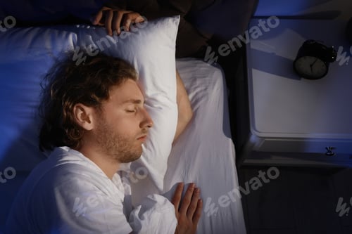 Preview: Handsome young man sleeping on pillow at night, view from above. Bedtime