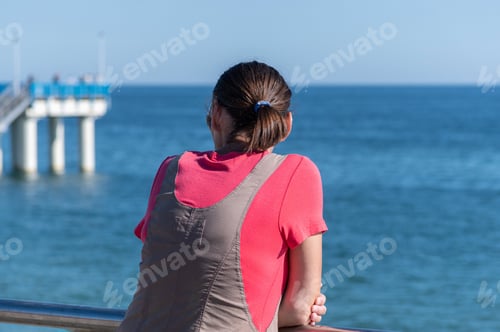 Preview: Woman dreams of traveling and looks at sea. Rear back view, copy space
