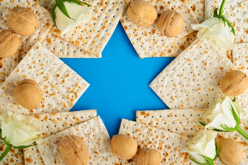 Preview: Passover celebration concept. Blue Star of David made from matzah, white and yellow roses, kippah an