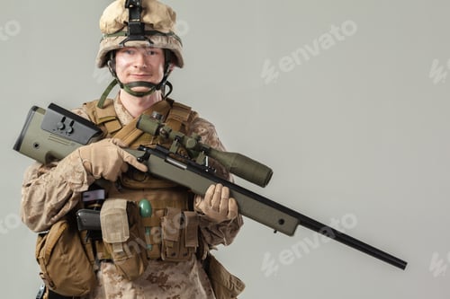 Preview: Soldier stands with rifle in studio setting during military portrait session