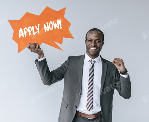 Preview: portrait of smiling african american businessman with apply now card isolated on grey