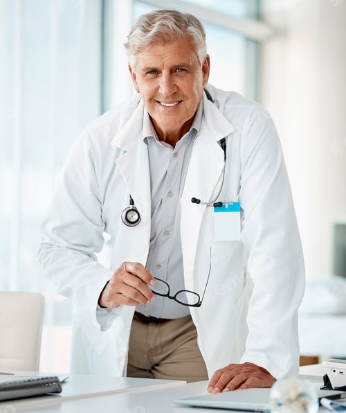 Preview: Experienced mature caucasian man doctor smiling and standing and holding his glasses in a hospital.