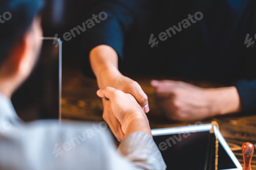 Preview: Closeup of unidentified young professionals and business people shaking hands after signing the deal