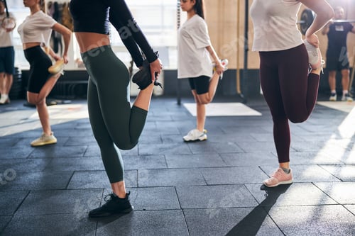 Preview: Fit young women stretching their legs while at gym
