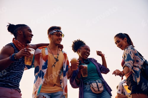 Preview: Young cheerful friends dancing while attending open air music concert during summer festival.