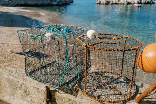 Preview: Fishing cages with weights stand on a stone fence by the sea