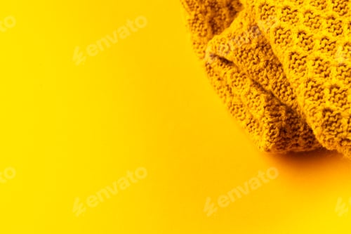 Preview: Micro close up of yellow wooly crochet fabric with copy space on yellow background