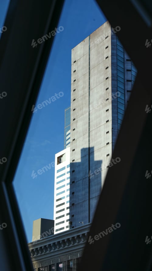 Preview: View of a skyscraper against a clear blue sky from a train window