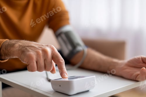 Preview: Man Using Digital Blood Pressure Monitor at Home