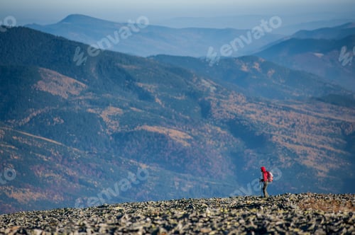 Preview: Male backpaker walking on the rocky top of the mountain