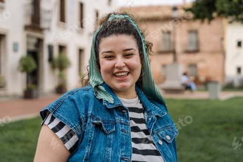 Preview: Young woman smiling outdoors in urban park setting