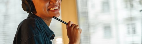 Preview: Smiling Afro american woman interior designer in headphones works with documents in home office