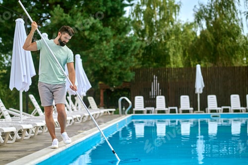 Preview: A service person cleaning the swimming pool and looking busy