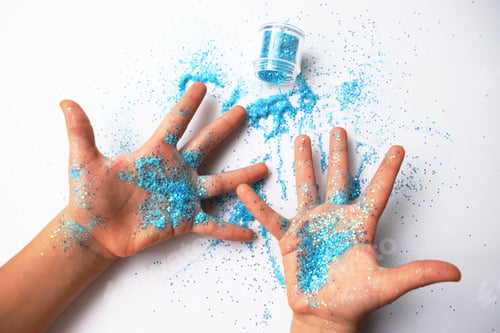 Child's Hands Covered in Glitter with Container Nearby