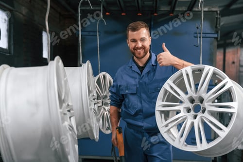 Preview: Showing thumb up. Car service station worker is taking care about disks of tires