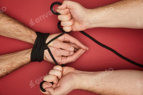 Preview: cropped view of man holding rope on tied boyfriend hands isolated on red