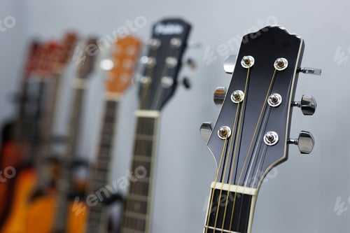 Preview: Close-up of the fingerboard of wooden guitars, ukulele on a guitar stand in the hall of music store.