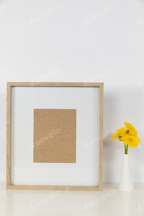Preview: View of a picture frame, with yellow tulips placed in a glass vase on plain white background