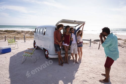 Preview: Capturing photos of his friends sitting in the trunk of a camper van against ocean and beach