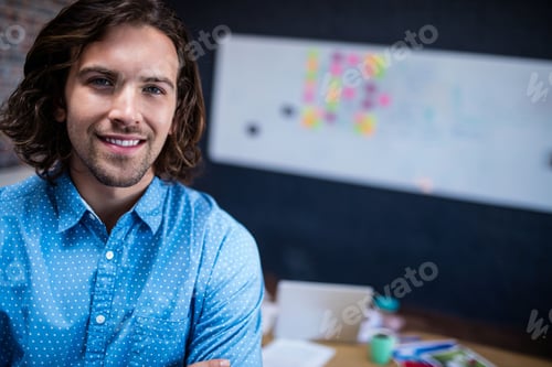 Preview: Young adult man standing at desk in office workspace, using laptop beside sticky notes, copy space