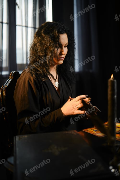 Preview: Woman reads tarot cards in a dimly lit room with candles and curtains during the evening